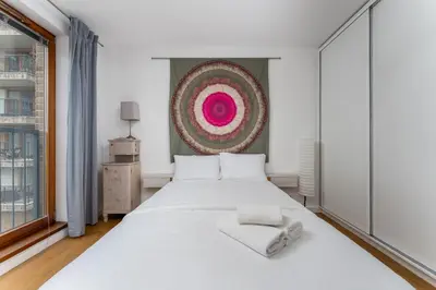 a bedroom with a white bed and a painting on the wall at Wilga Park Homely Apartment by BookingHost in Kraków