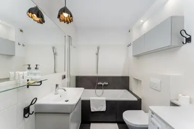 a kitchen with white cabinets and a white table at Wilga Park Homely Apartment by BookingHost in Kraków