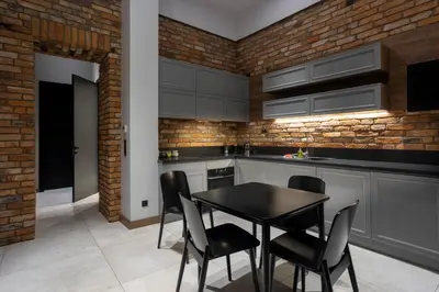 a kitchen with a table and chairs and a brick wall at Tyzenhauz Apartments Superior in Kraków