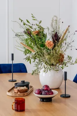 a table with a vase of flowers and a plate of fruit at Tyzenhauz Apartments Superior in Kraków