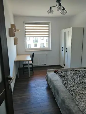 a bedroom with a bed and a desk and a window at Fajny Apartament EXPO TAURON ARENA in Kraków