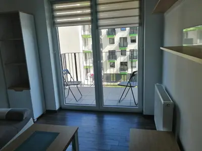 a living room with a sliding glass door with a balcony at Fajny Apartament EXPO TAURON ARENA in Kraków