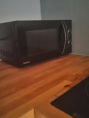 a microwave oven sitting on top of a wooden floor at Fajny Apartament EXPO TAURON ARENA in Kraków