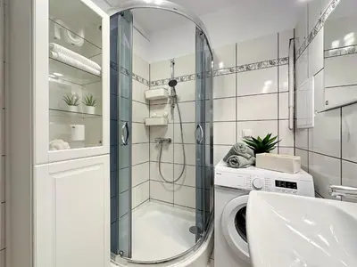 a bathroom with a shower and a washing machine at Vista Kraków Ugorek in Kraków