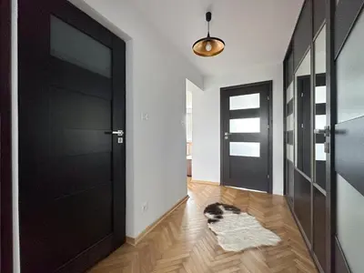 a hallway with a black door and a dog laying on the floor at Vista Kraków Ugorek in Kraków