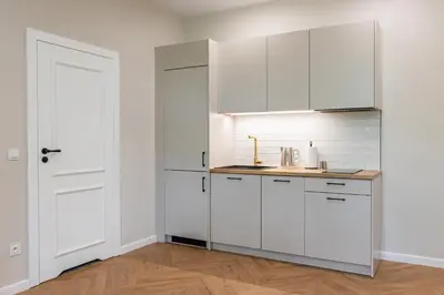 an empty kitchen with white cabinets and a door at Między Wawelem a Rynkiem in Kraków