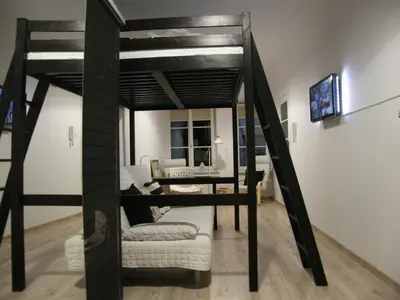 a loft bed with a desk and a couch in a room at Apartament Jagielloński in Kraków