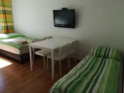 a room with a table and a bed and a tv at Apartamenty Asia Kraków in Kraków