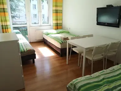 a room with a table and a bed and a tv at Apartamenty Asia Kraków in Kraków