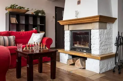 a living room with a red couch and a fireplace at Spacious house in the rural suburbs of Krakow in Zagacie