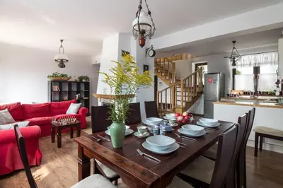 a dining room and living room with a wooden table at Spacious house in the rural suburbs of Krakow in Zagacie