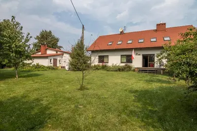 a white house with a red roof and a yard at Spacious house in the rural suburbs of Krakow in Zagacie