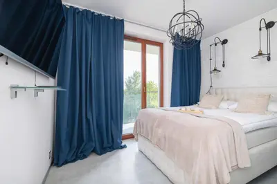 a bedroom with blue curtains and a bed and a window at Żabiniec Stylish Apartment in Cracow with Balcony by Noclegi Renters in Kraków