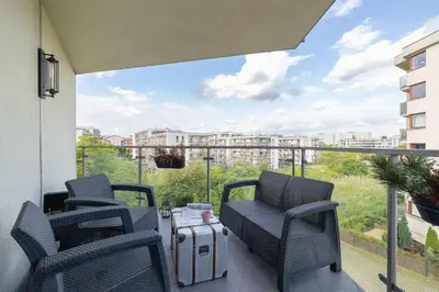 a patio with chairs and a suitcase on a balcony at Żabiniec Stylish Apartment in Cracow with Balcony by Noclegi Renters in Kraków