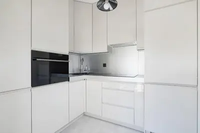 a white kitchen with white cabinets and a sink at Żabiniec Stylish Apartment in Cracow with Balcony by Noclegi Renters in Kraków