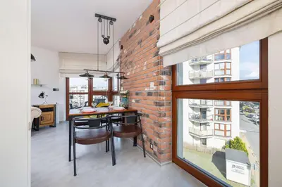 a brick wall in a kitchen with a table and chairs at Żabiniec Stylish Apartment in Cracow with Balcony by Noclegi Renters in Kraków