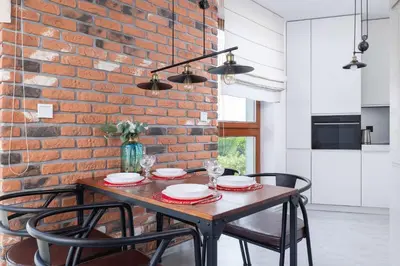 a dining room table with chairs and a brick wall at Żabiniec Stylish Apartment in Cracow with Balcony by Noclegi Renters in Kraków