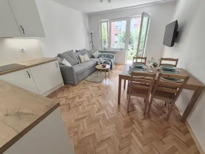 a kitchen and living room with a table and a couch at Dąbie Park Apartament in Kraków