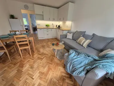 a living room with a couch and a table and a kitchen at Dąbie Park Apartament in Kraków
