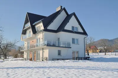a white bed with white sheets and pillows at Apartamenty w sadzie in Przenosza