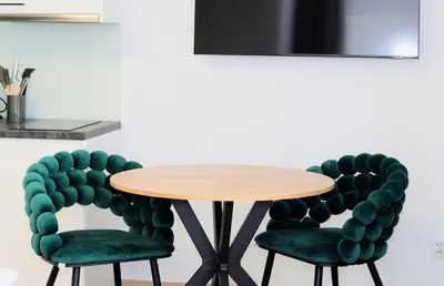 a table and two green chairs in a room at Apartamenty w sadzie in Przenosza
