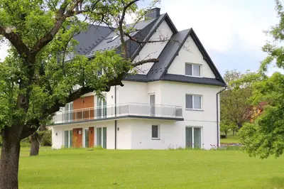 a large white house with a black roof at Apartamenty w sadzie in Przenosza