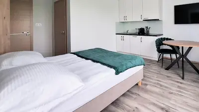 a white bedroom with a bed and a table at Apartamenty w sadzie in Przenosza