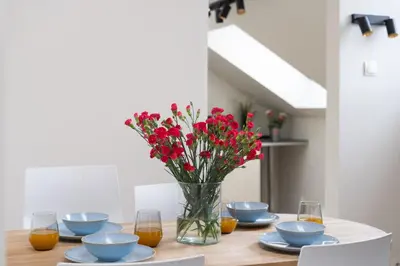 a table with a vase with red flowers in it at Tomasza 20 Apartment in Kraków