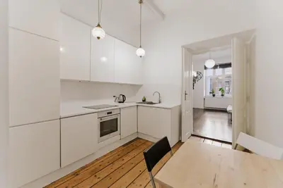 a kitchen with white cabinets and a wooden table at Traugutta Loft in Kraków