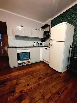 a kitchen with a white refrigerator and a wooden floor at Comfy Corners in Kraków