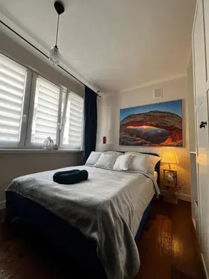 a bedroom with a large bed with a painting on the wall at Comfy Corners in Kraków
