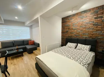 a bedroom with a brick wall and a bed and a couch at Rzeszowska 5 Apt 02 in Kraków