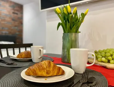 a table with two plates of croissants and two cups at Rzeszowska 5 Apt 02 in Kraków