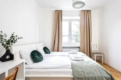 a bedroom with a white bed with green pillows at Kazimierz Hideaway by Upstairs in Kraków