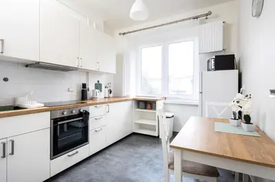 a kitchen with white cabinets and a wooden table at Kazimierz Hideaway by Upstairs in Kraków