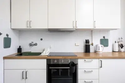 a kitchen with white cabinets and a black oven at Kazimierz Hideaway by Upstairs in Kraków