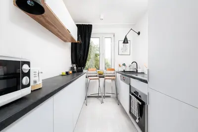 a kitchen with white cabinets and black countertops at Quiet Quarter - by Upstairs in Kraków