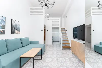 a living room with a blue couch and a tv at Zakopiańska 2B Homely Apartment by BookingHost in Kraków