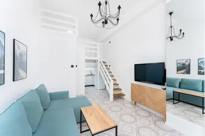 a living room with a blue couch and a tv at Zakopiańska 2B Homely Apartment by BookingHost in Kraków