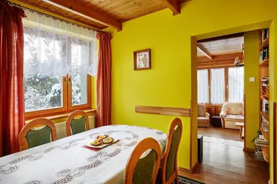 a dining room with a table and a yellow wall at Drewniany Dom Rabka Zdrój in Rabka