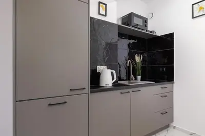 a kitchen with white cabinets and black tiles at Cozy Studios in the Old Town of Kraków by Noclegi Renters in Kraków