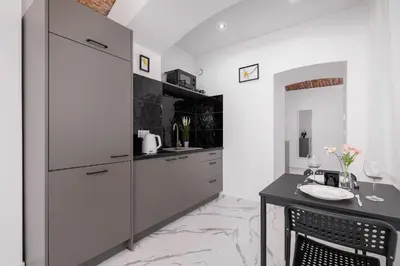 a kitchen with white cabinets and a table at Cozy Studios in the Old Town of Kraków by Noclegi Renters in Kraków