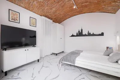 a bedroom with a bed and a flat screen tv at Cozy Studios in the Old Town of Kraków by Noclegi Renters in Kraków
