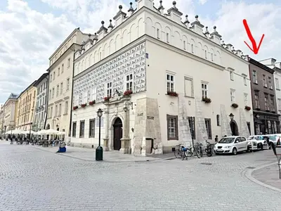 a large white building on a street with a red arrow at The Heritage House Aparthotel Main Square Self Check-In in Kraków