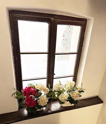 a window with flowers on a window sill at The Heritage House Aparthotel Main Square Self Check-In in Kraków