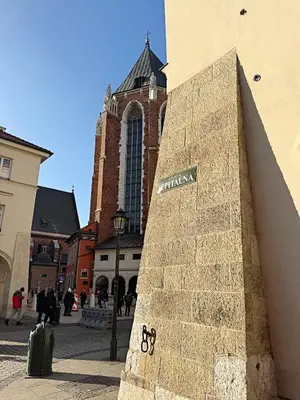 a brick wall with a sign on it in front of a church at The Heritage House Aparthotel Main Square Self Check-In in Kraków