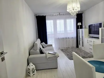 a kitchen with white cabinets and a table and chairs at Słoneczne mieszkanie wśród zieleni in Kraków