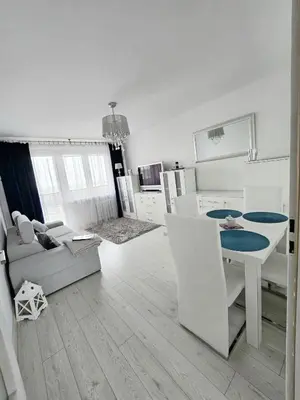 a small white kitchen with a bed and a table at Słoneczne mieszkanie wśród zieleni in Kraków