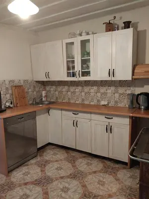 a kitchen with white cabinets and a tile floor at Chatka na Lipowych Wzgórzach in Marcówka