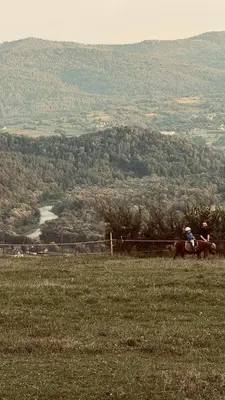 two people sitting on a horse in a field at Chatka na Lipowych Wzgórzach in Marcówka